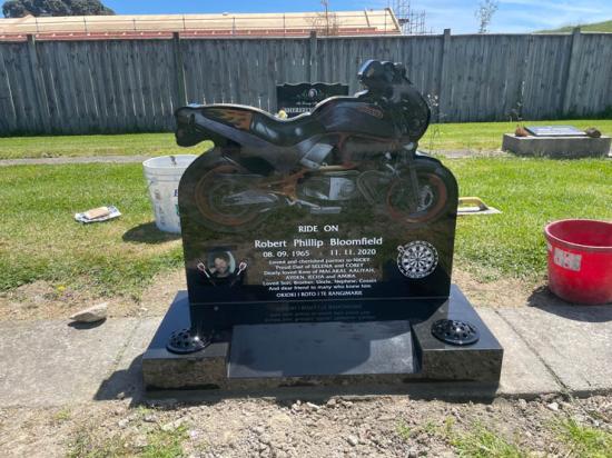 Custom upright headstone with motorbike shape and engravings, crafted from polished granite by Mark Memorials in Levin, New Zealand.