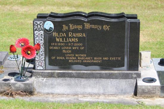 Classic upright double headstone in a book shape, with maori carved designs and a photo. Crafted from polished granite by Mark Memorials in Levin, New Zealand.
