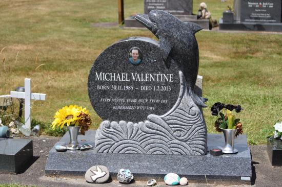 Custom upright headstone with carved dolphin and stylised waves, crafted from polished granite by Mark Memorials in Levin, New Zealand