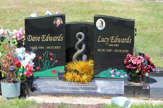 Modern upright double headstone with split low saddle shape and koru, crafted from polished granite, by Mark Memorials in Levin, New Zealand.