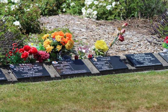 Black granite cremation plaques mounted around a garden